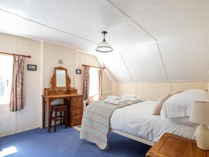 Ein Schlafzimmer mit einem Bett, einer Holzkommode, einem Schreibtisch und einem Deckenventilator.