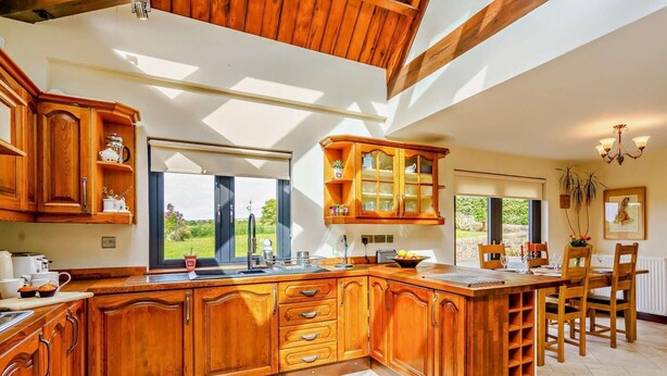Een ruime keuken met houten kasten, een groot eiland en uitzicht op de omgeving.