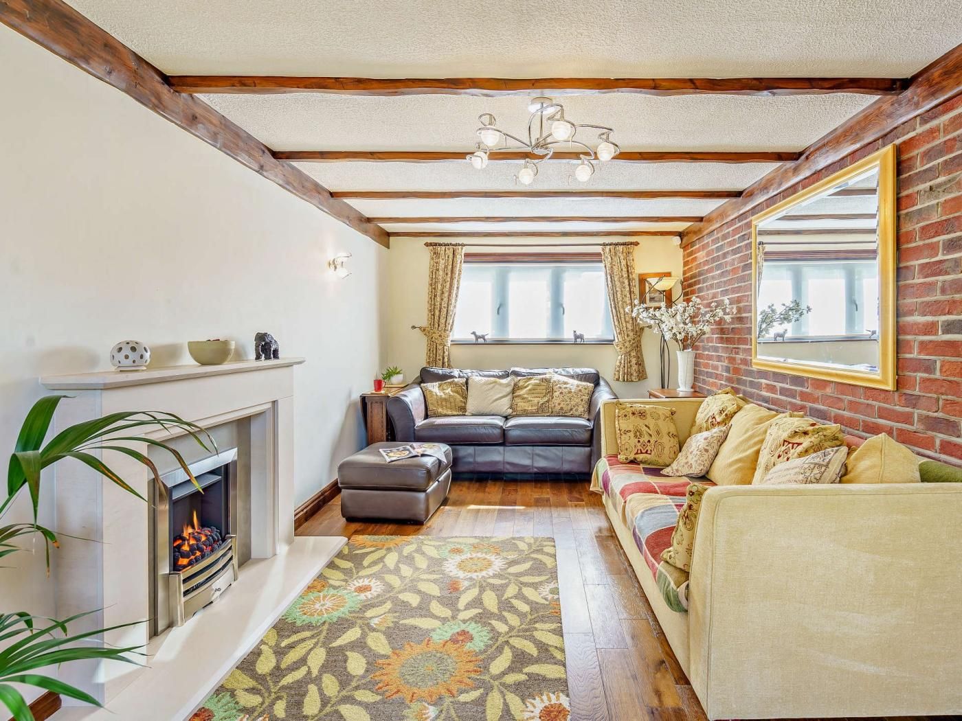Una sala de estar con chimenea, un sofá, un sillón y una alfombra estampada.