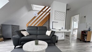 Un salon moderne comprenant un canapé, une table basse, un bureau et un escalier.