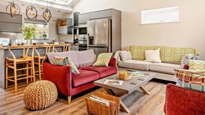 A modern kitchen with a dining area, a red sofa, and a patterned sofa.