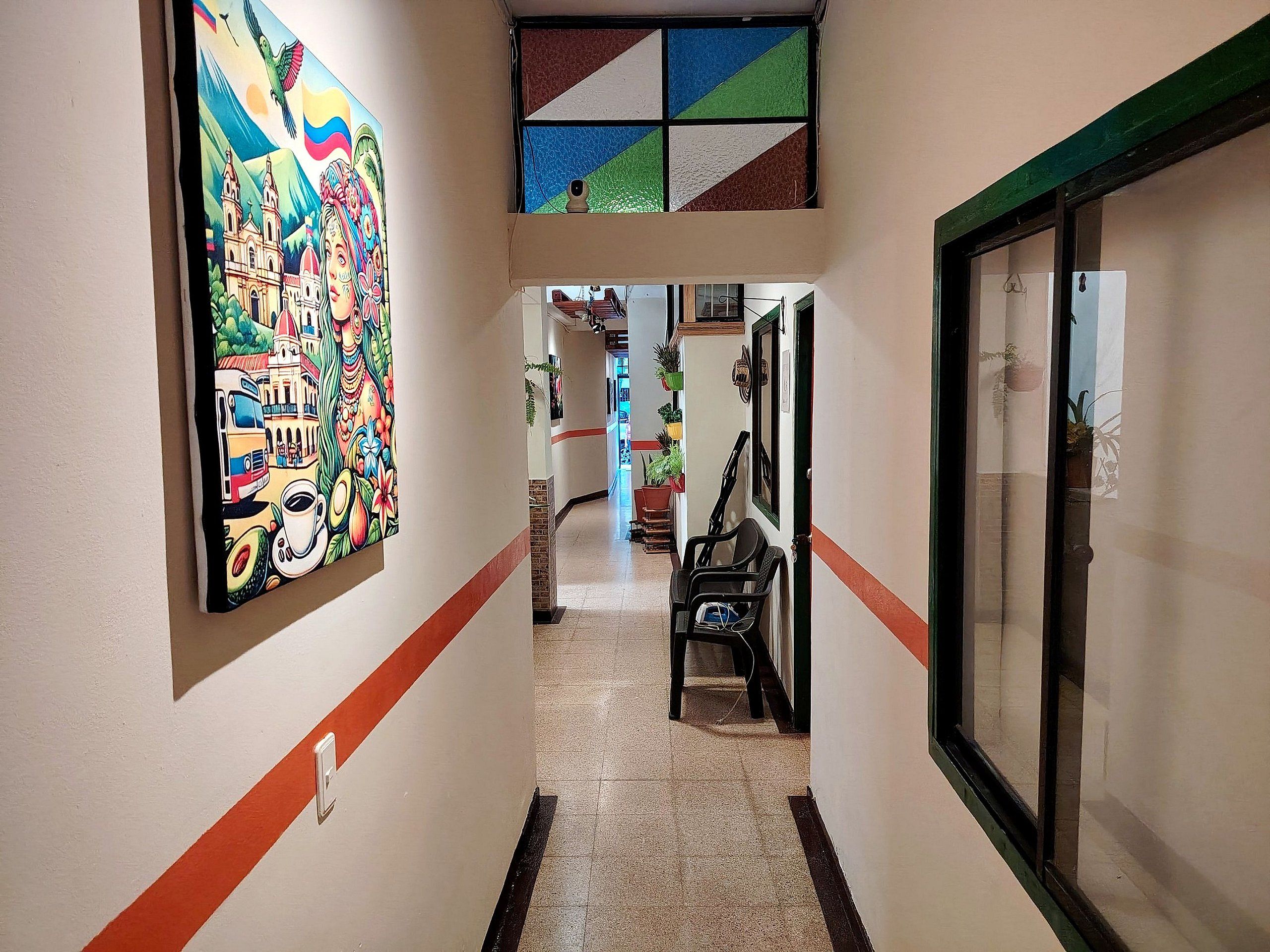 A hallway with a colorful mural, a tiled floor, and a door with a green frame.