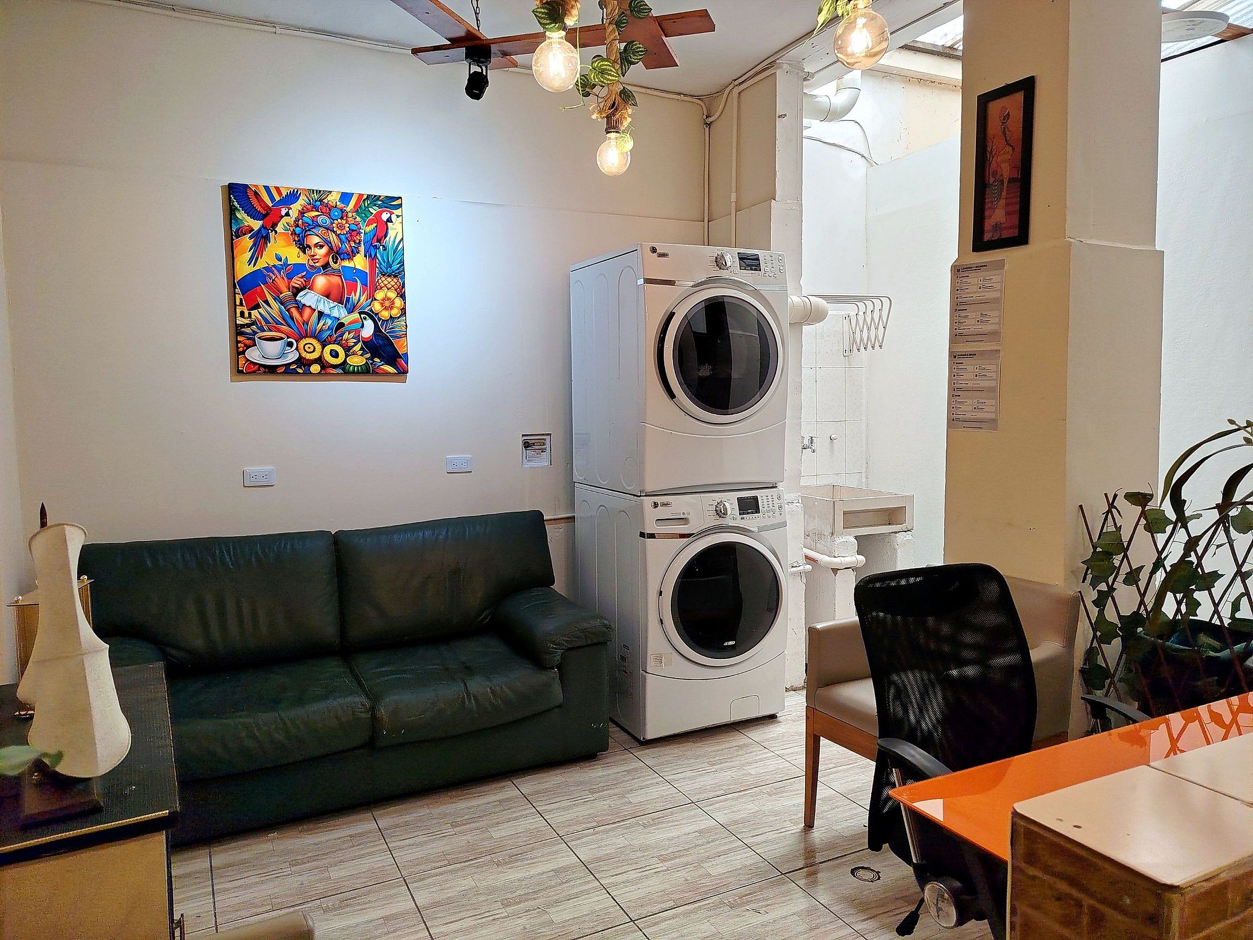 Un salon avec un canapé vert, un lave-linge, une table à manger et un ventilateur de plafond.