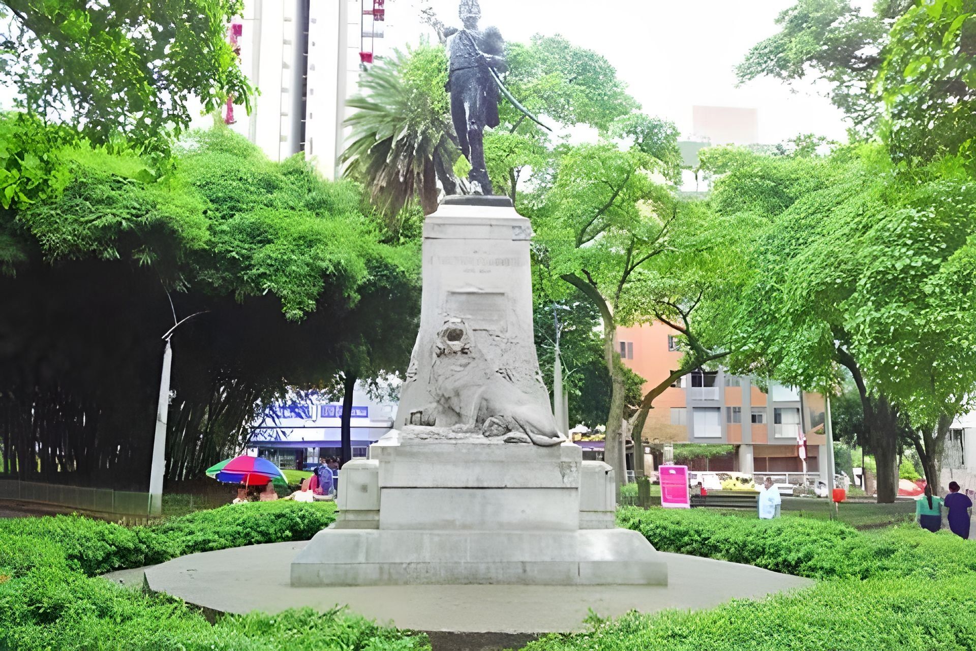 Eine Statue in einem Park, im Hintergrund Bäume und Gebäude.
