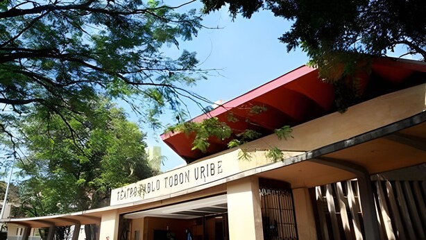 Um edifício com uma placa que diz 'TEJADO TOBO URIBE' e uma entrada coberta.