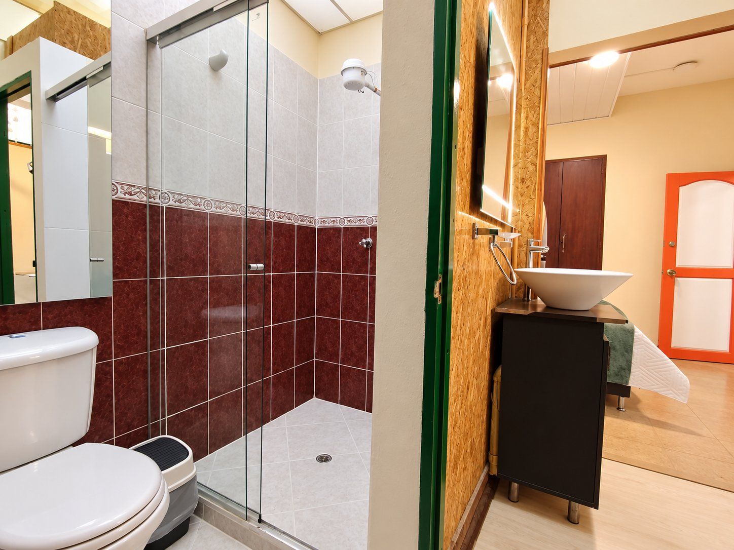 A bathroom with a glass shower enclosure, a toilet, and a sink with a wooden vanity.