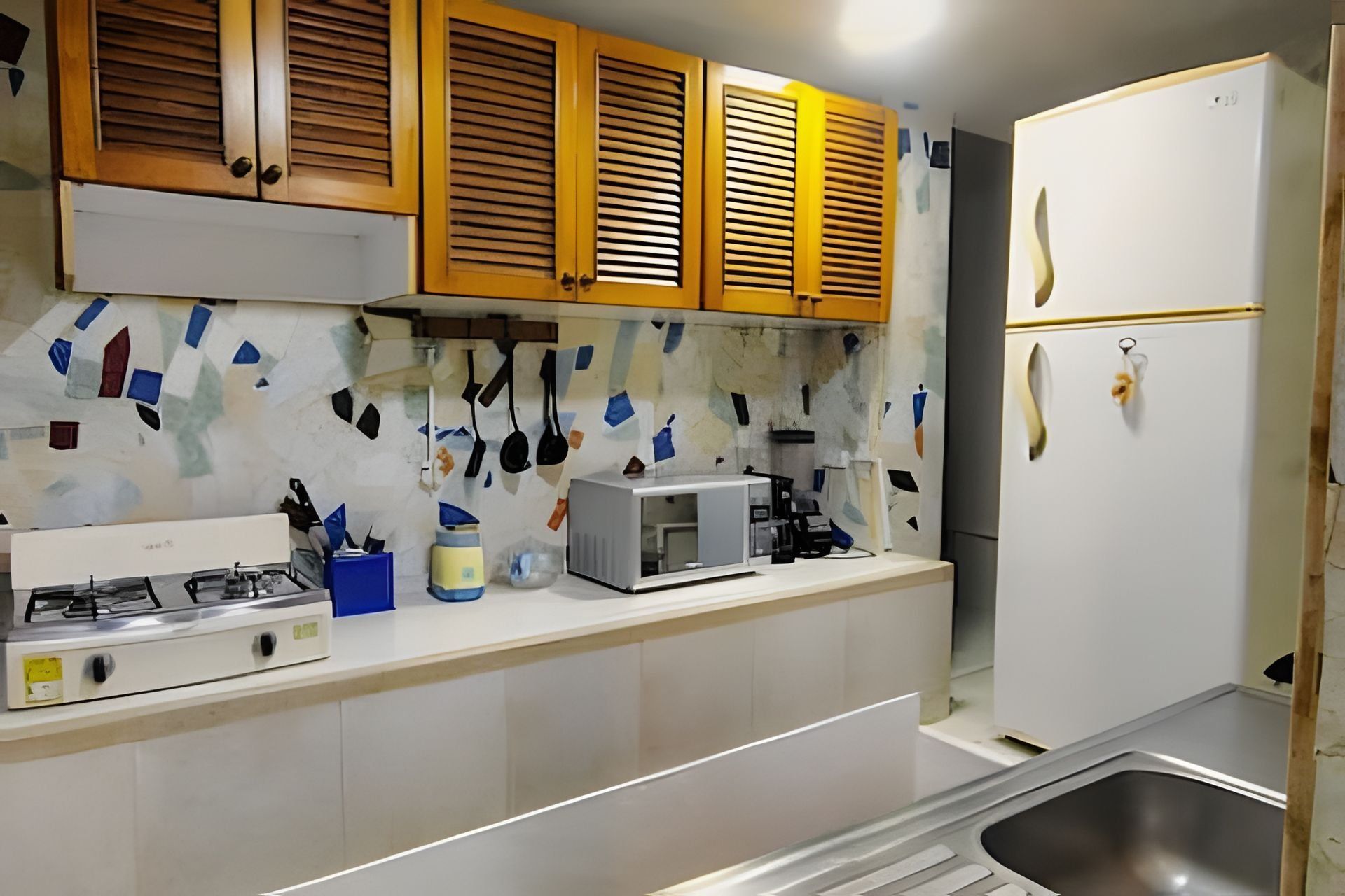 A kitchen with wooden cabinets, a microwave, a gas stove, and a stainless steel sink.