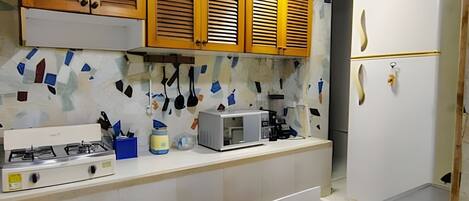 A kitchen with wooden cabinets, a microwave, a gas stove, and a stainless steel sink.
