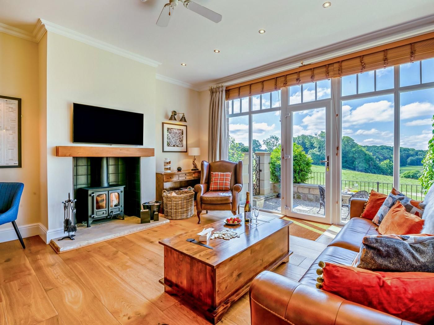 A spacious living room with a fireplace, a television, and a large window offering a view of the outdoors.