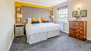 Une chambre à coucher avec un grand lit, des tables de chevet, une commode et des tableaux encadrés accrochés aux murs.