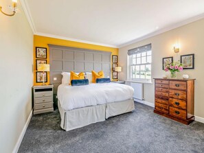 Ein Schlafzimmer mit einem großen Bett, Nachttischen, einer Kommode und gerahmten Bildern an den Wänden.