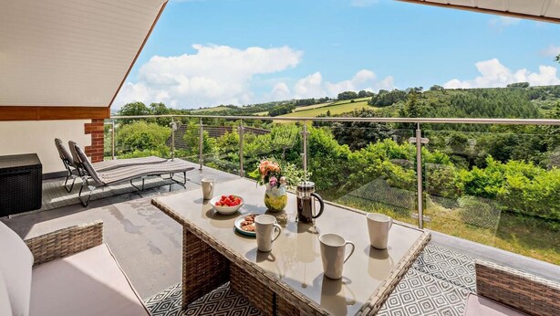Un balcon avec une table, des chaises et une vue sur la campagne.