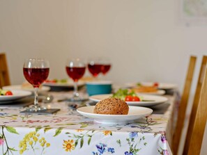 Ein Esstisch mit einer blumigen Tischdecke, ein Teller mit einem gebackenen Gebäck und Gläser mit Rotwein.