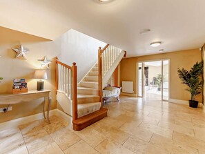 A spacious living area with a wooden staircase, a radiator, and a large potted plant. - 6 Bed in Morpeth (oc-91805) (Ellington)