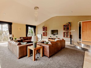 A spacious living room with a large sofa set, a coffee table, a TV, and built-in shelving. - 6 Bed in Morpeth (oc-91805) (Ellington)
