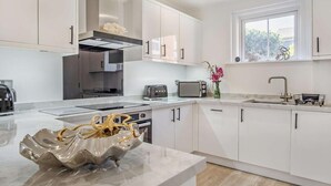 Una cucina moderna con mobili bianchi, elettrodomestici in acciaio inossidabile e una ciotola decorativa sul piano di lavoro.