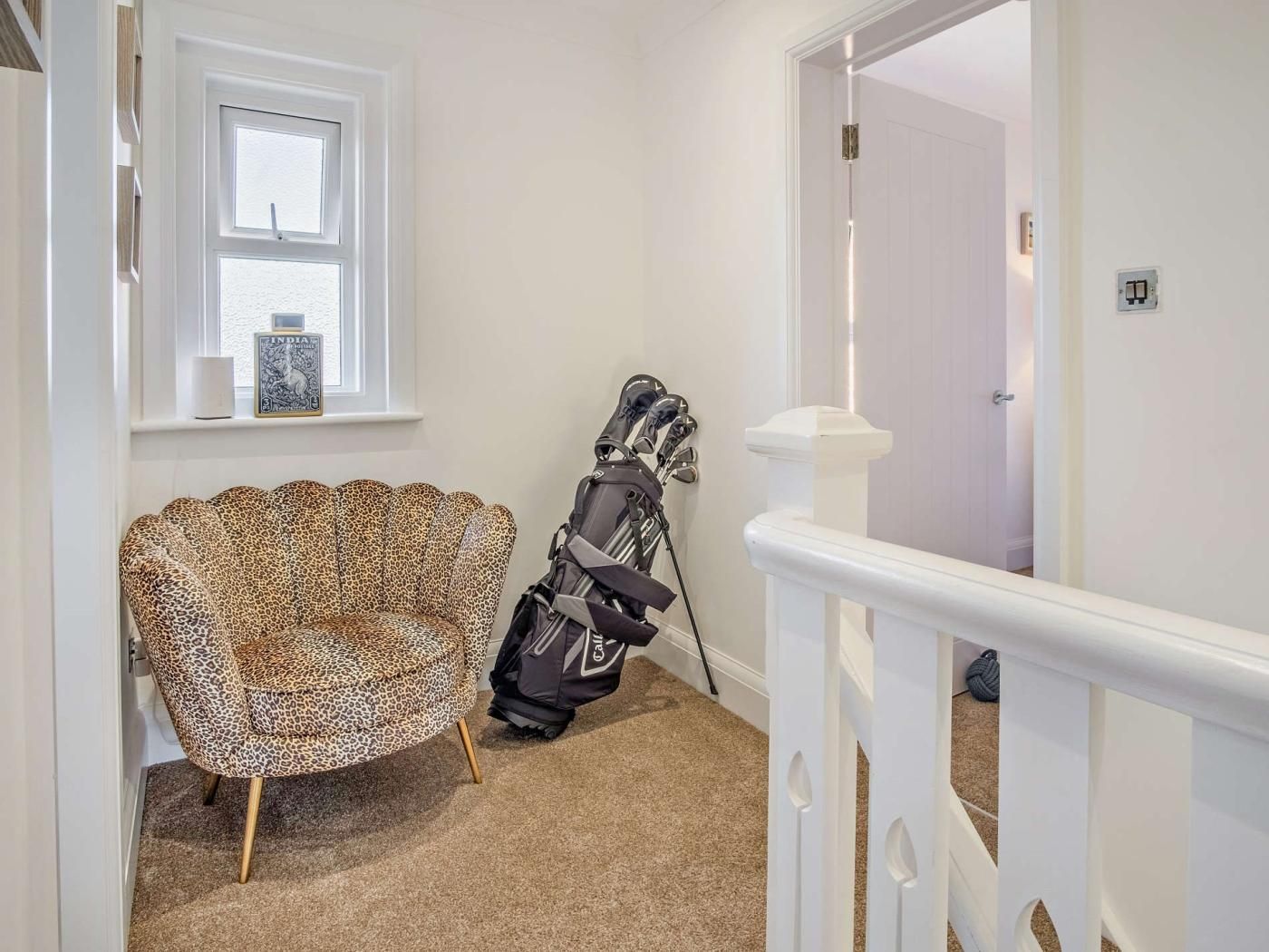 Et værelse med en sofa med leopardmønster, en golftaske og et hvidt gelænder.
