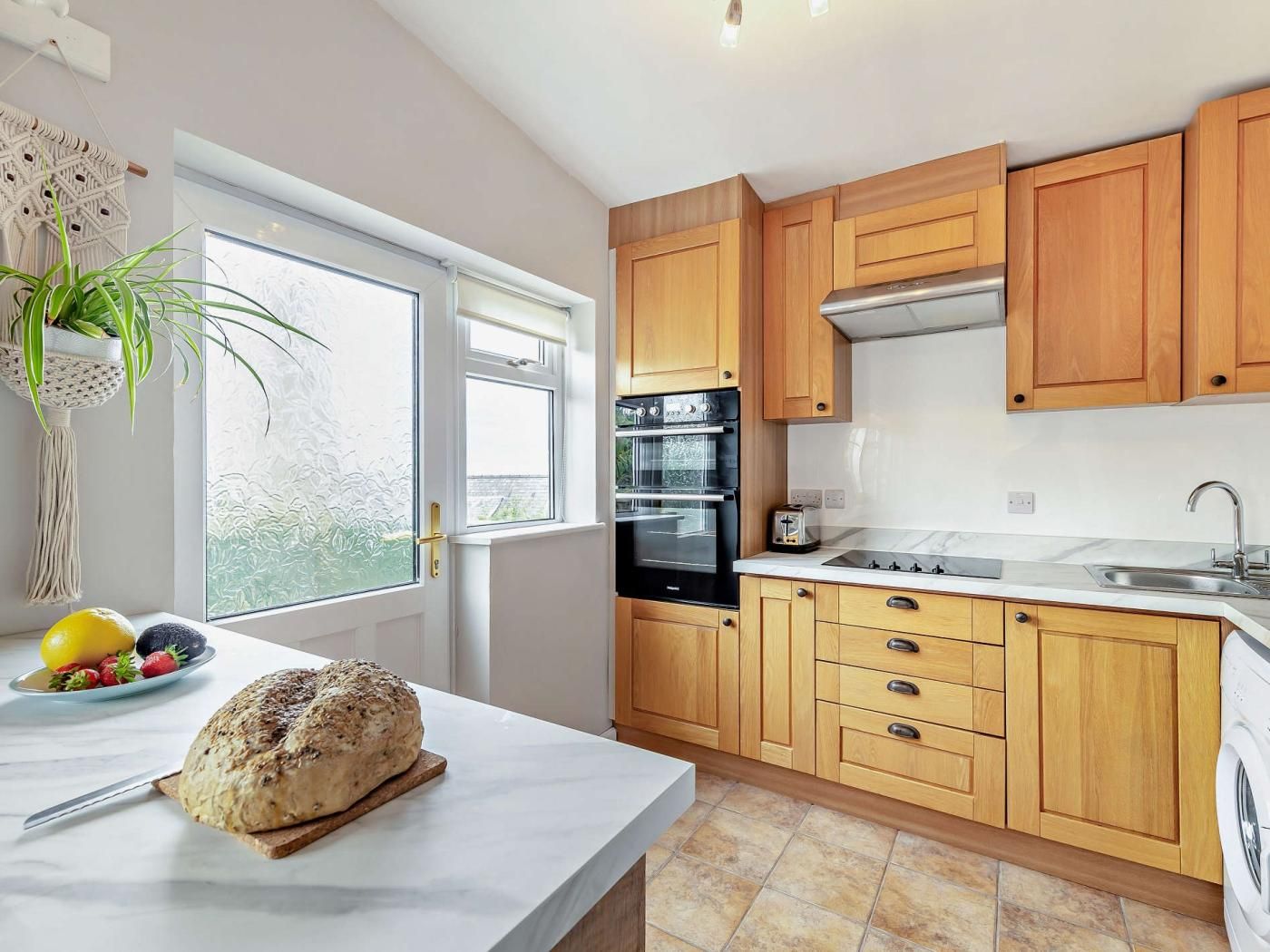 A modern kitchen with wooden cabinets, a built-in oven, and a large window.