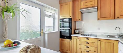 A modern kitchen with wooden cabinets, a built-in oven, and a large window.