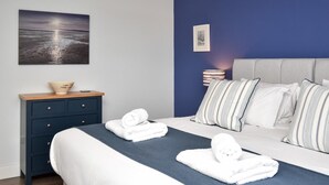 Ein ordentlich eingerichtetes Schlafzimmer mit einem Bett, Kissen, einem Nachttisch und einer Wandleuchte.
