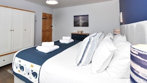 Ein Schlafzimmer mit einem Bett, einer Holztür, einem Nachttisch und einem an der Wand hängenden Bild.