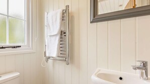 Ein Badezimmer mit einem weißen Waschbecken, einem Spiegel und einem Handtuchhalter.