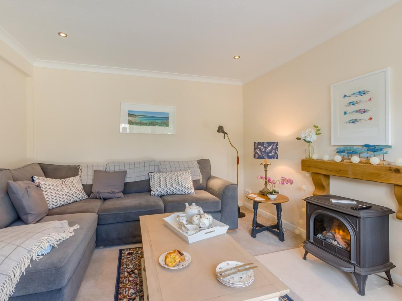 A living room with a sofa, a coffee table with a teapot and plates, a fireplace, and a framed picture on the wall.