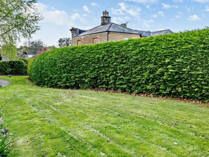 A well-maintained hedge, a grassy lawn, and a stone building with a pitched roof. - 2 Bed in South Petherton (oc-91952) (South Petherton)