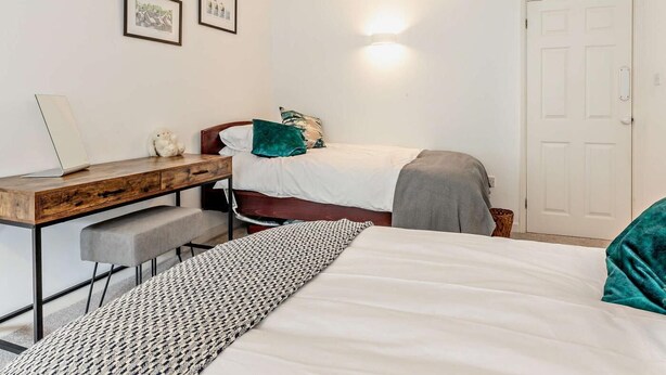 A bedroom with a bed, a desk, and a chair. There are two framed pictures on the wall. - 2 Bed in South Petherton (oc-91952) (South Petherton)