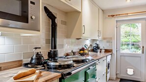 A kitchen with a microwave, stove, and green cabinets. - 2 Bed in South Petherton (oc-91952) (South Petherton)