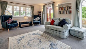 A cozy living room with a sofa, two armchairs, a coffee table, and a bookshelf. - 2 Bed in South Petherton (oc-91952) (South Petherton)