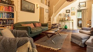 Ein geräumiges Wohnzimmer mit einem grünen Sofa, einem Couchtisch und einem Bücherregal voller Bücher.