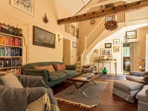 Ein geräumiges Wohnzimmer mit einem grünen Sofa, einem Couchtisch und einem Bücherregal voller Bücher.