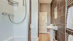 Un bany modern amb dutxa tancada amb vidre, un lavabo blanc i una barra de tovalloles.