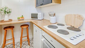 Eine Küche mit Mikrowelle, Herd, zwei Barhocker, Spüle und Schrank.