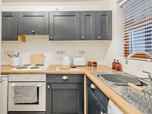 A modern kitchen with grey cabinets, a wooden countertop, a built-in oven, a sink, and a window with blinds. - 2 Bed in Keswick (oc-91901) (Keswick)