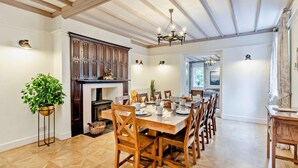 Un comedor con una mesa y sillas de madera, una chimenea y un candelabro.