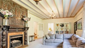 Una sala de estar con chimenea, un sofá, una estantería y una araña.