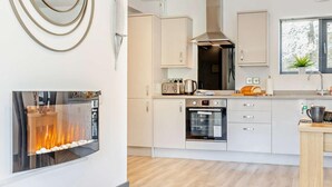 Eine moderne Küche mit eingebauten Geräten, einer Kochinsel und einem Kamin.