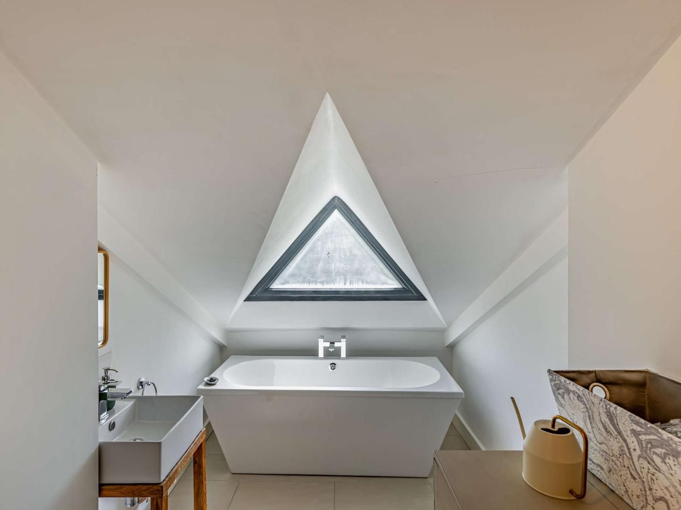 A modern bathroom with a freestanding bathtub, a skylight, and a small window.