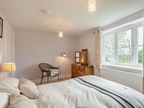 A bedroom with a bed, a chair, a dresser, a lamp, and a window. - 4 Bed in Skegness (oc-92368) (Anderby)