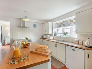 A modern kitchen with white cabinetry, a wooden countertop, a built-in oven, and a window with a view. - 4 Bed in Skegness (oc-92368) (Anderby)