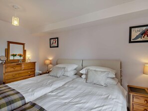 Ein Schlafzimmer mit einem großen Bett, einem Schminktisch, einem Spiegel und zwei Wandlampen.