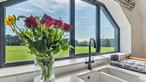 Eine Küche mit großem Fenster, Blumen in einer Vase und einem modernen Wasserhahn.