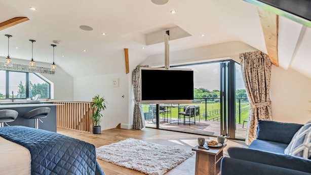 Ein modernes Wohnzimmer mit großem Fernseher, Essbereich und Balkon mit Blick.