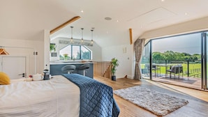 Ein modernes Schlafzimmer mit einem großen Bett, einem Schreibtisch, Blick ins Freie und einem Balkon.