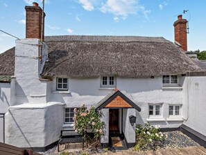 A traditional white cottage with a thatched roof, a small front porch, and a chimney. - 2 Bed in Braunton (oc-92387) (Croyde)