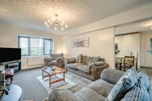 A living room with a sofa set, a television, and a chandelier. - 3 Bed in Grange-over-sands (oc-92389) (Upper Allithwaite)