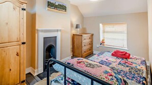 A bedroom with a bed, a wooden wardrobe, a fireplace, a window with blinds, and a ceiling light. - 2 Bed in Fakenham (oc-92173) (Fakenham)