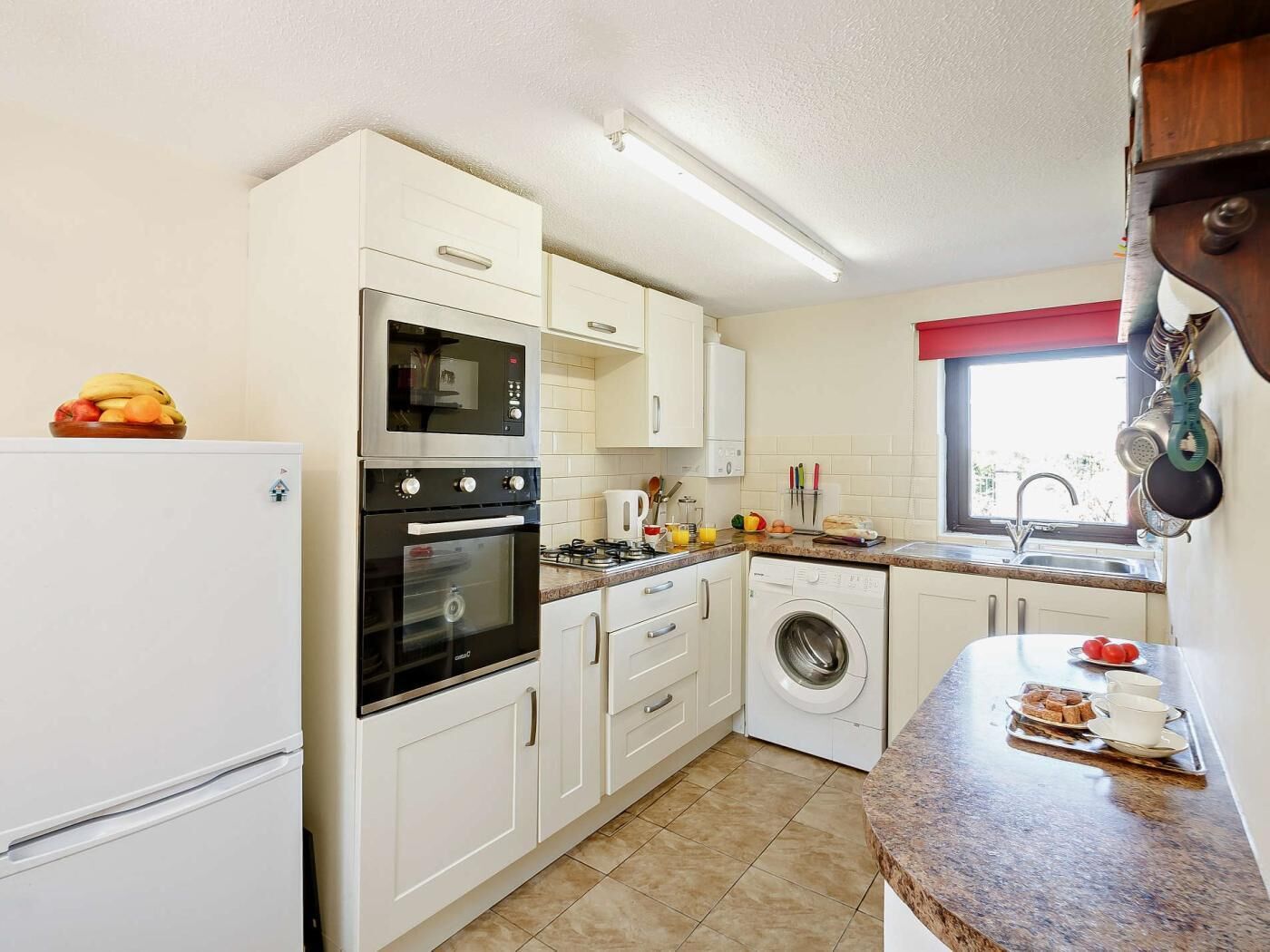 Eine kompakte Küche mit Kühlschrank, Backofen, Mikrowelle, Waschmaschine und Spüle.